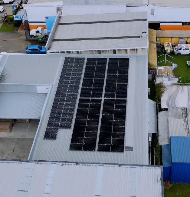 Aerial view of a commercial solar panel system installed on a large metal warehouse roof