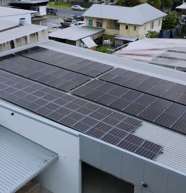Rows of solar panels installed on a large commercial warehouse roof, with a loading bay below