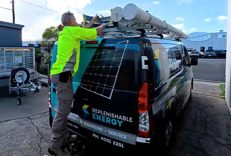 Replenishable Energy technician loading equipment onto the roof rack of a branded service van