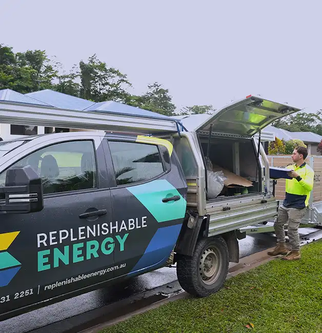 Replenishable Energy installer checking a job sheet beside a branded ute at a residential job site