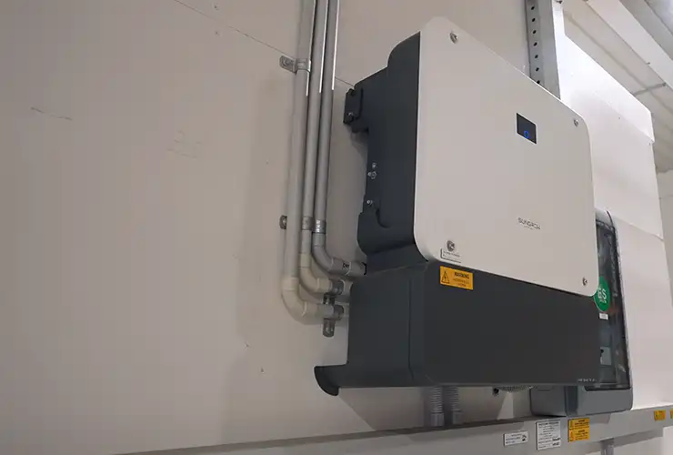 Wall-mounted Sungrow inverter with neatly run conduit and cabling beside a switchboard